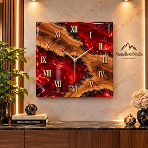 May include: A square wall clock featuring a natural wood slab with live edges integrated into a glossy, deep red resin background. The clock face displays gold-colored Roman numerals and thin gold hands. The text StoneResinStudio is visible.