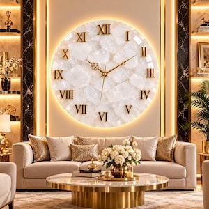 May include: A large circular wall clock featuring a textured white stone face with gold-colored Roman numerals and thin gold hands. The clock is backlit with a warm glow, creating a halo effect against the wall behind it.