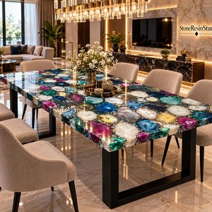 May include: A rectangular dining table featuring a tabletop composed of multicoloured agate slices in shades of blue, purple, green, and white, set in a resin finish. The table has a black metal frame with four legs and is surrounded by beige chairs.