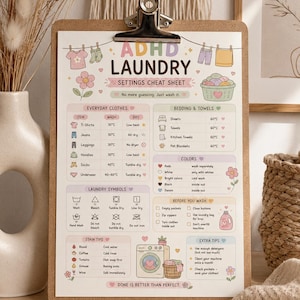 May include: A clipboard holding a printed ADHD Laundry Settings Cheat Sheet with pastel illustrations of clothing, a washing machine, and flowers. The document includes sections for everyday clothes, bedding, laundry symbols, colors, and stain tips.