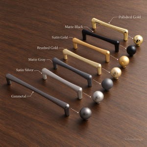 Puede incluir: Una colección de herrajes para armarios con tiradores arqueados y pomos esféricos en varios acabados, incluyendo oro pulido, negro mate, oro satinado, oro cepillado, gris mate, plata satinada y bronce, etiquetados con sus nombres.