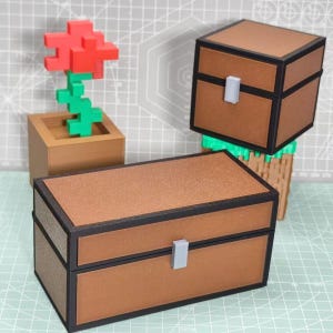 Puede incluir: Dos cofres de almacenamiento rectangulares de color marrón con bordes negros y un pequeño pestillo gris, acompañados de una flor roja pixelada en una maceta cuadrada marrón. Los objetos tienen un diseño cúbico con superficies texturizadas.
