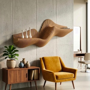 Può includere: Una mensola in legno a parete con un design ondulato e stratificato che sostiene tre vasi bianchi. Sotto, un mobile in legno con due ante e un ripiano aperto si trova accanto a una poltrona imbottita color giallo senape su un pavimento in cemento.