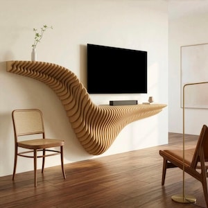 Peut inclure: Une étagère flottante fixée au mur présentant une structure en bois brun clair, superposée et ondulée, qui s'étend horizontalement. Un téléviseur à écran plat est fixé au-dessus de l'étagère et un petit vase blanc avec une plante verte est posé à gauche.
