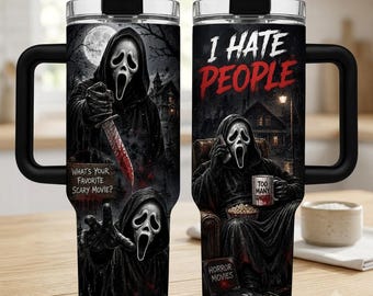 May include: A black stainless steel tumbler with a handle and clear lid, featuring a graphic of a masked figure in a black robe. One side shows the figure holding a bloody knife with the text "WHAT'S YOUR FAVORITE SCARY MOVIE?" The other side shows the figure holding a phone and a mug with the text "I HATE PEOPLE" and "TOO MANY IDIOTS".