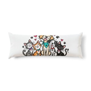 Pode incluir: Uma almofada retangular branca com uma ilustração colorida de desenho animado de dois gatos, dois cães e um filhote sentados juntos. Os animais usam coleiras com pingentes de coração e bandanas, cercados por pequenos corações rosas e patas.