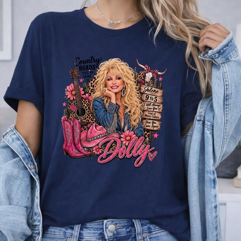 May include: A navy blue t-shirt featuring a graphic print of a blonde woman with a guitar, pink cowboy boots, a pink hat, and a wooden sign listing song titles including Jolene, 9 to 5, I Will Always Love You, and Coat of Many Colors.