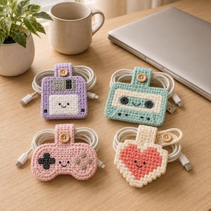 May include: Four crocheted cable organizers featuring a light purple floppy disk, a light green cassette tape, a light pink game controller, and a cream-colored heart, each with a small wooden button closure and a white charging cable wrapped inside.