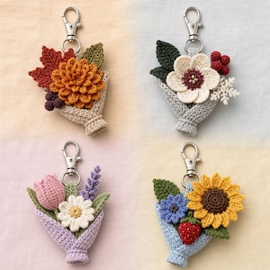 May include: Four crochet flower bouquet keychains with silver lobster clasps. Top left: orange dahlia, red maple leaf, and dark berries. Top right: white flower, green leaves, red berries, and snowflake. Bottom left: pink tulip, white daisy, and lavender. Bottom right: yellow sunflower, blue flower, and red strawberry.