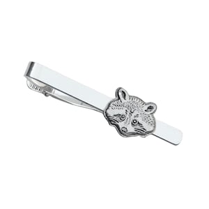 May include: A silver tie bar with a raccoon face design.