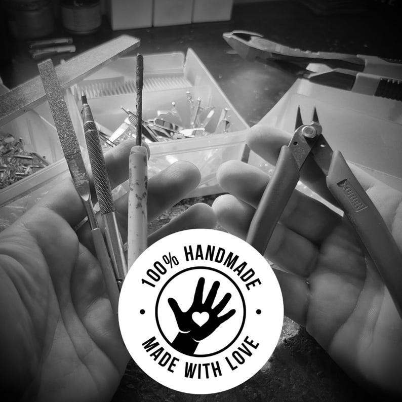 Puede incluir: Imagen en blanco y negro de una mano sosteniendo varias herramientas, incluyendo una lima, un destornillador y un alicate. Un c&iacute;rculo blanco con texto negro dice "100% HANDMADE MADE WITH LOVE" y presenta una mano negra con un coraz&oacute;n en la palma.