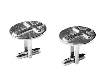 May include: A pair of silver cufflinks with a cross design. The cufflinks are round and have a textured surface.
