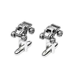 May include: A pair of silver cufflinks featuring a detailed miniature off-road vehicle design.