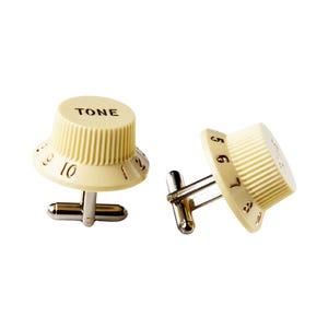 Puede incluir: Un par de gemelos con forma de botones de guitarra vintage. Un botón está etiquetado como "TONE" y el otro tiene los números del 5 al 8.
