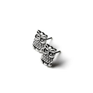 May include: A pair of silver-toned owl stud earrings featuring a detailed, textured feather pattern on the body and prominent eyes. Each earring has a post back for secure attachment, showcasing a metallic finish with darkened recessed areas.