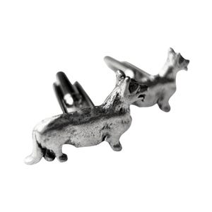 May include: A pair of silver cufflinks featuring a detailed design of a Welsh Corgi dog.