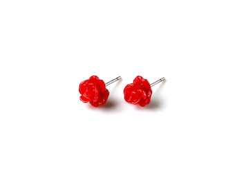May include: A pair of silver stud earrings with red rose-shaped charms.