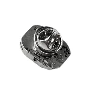 Pode incluir: Um alfinete de metal prateado com um design detalhado que se assemelha a um mecanismo de relojoaria. O alfinete tem um fecho redondo prateado.