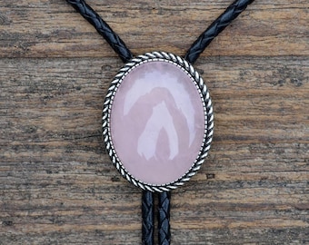 Peut inclure: Un bolo tie avec une pierre précieuse rose sertie dans un ovale argenté et un cordon tressé noir.