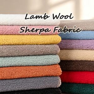 Könnte beinhalten: Ein Stapel gefalteter Lamb Wool Sherpa Stoff in verschiedenen Farben wie Weiß, Rosa, Gelb, Grau, Hellgrün, Orange, Dunkelgrau, Schwarz, Beige, Blau, Lila, Braun, Rot und Dunkelgrün, mit dem sichtbaren Text Lamb Wool Sherpa Fabric.