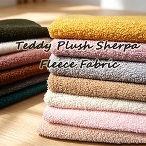 Könnte beinhalten: Ein Stapel gefalteter Teddy-Plüsch-Sherpa-Fleece-Stoff in verschiedenen Farben wie Gelb, Rosa, Grau, Beige und Weiß. Der Stoff hat eine dicke, strukturierte Oberfläche mit lockigem Flor. Der Text Teddy Plush Sherpa Fleece Fabric ist sichtbar.