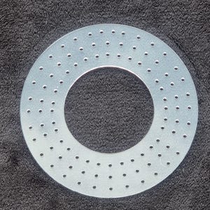 May include: A circular, translucent acrylic disc featuring a large centre cutout and multiple rows of small, evenly spaced perforations arranged in a concentric pattern across the flat surface of the material.
