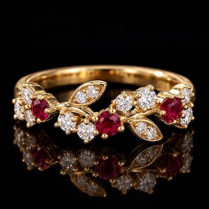 Puede incluir: Un anillo de oro con un diseño en forma de rama, adornado con tres rubíes rojos de talla redonda y múltiples diamantes blancos transparentes pequeños. La banda es de oro amarillo pulido y el engaste muestra un arreglo floral de gemas.