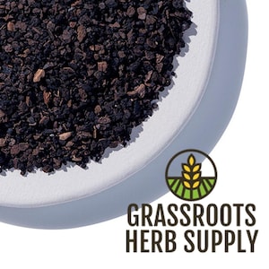 May include: A close-up of a white ceramic dish filled with dark brown, dried, and crumbled bark. The dish is on a white surface. The text "GRASSROOTS HERB SUPPLY" is in the lower right corner of the image.
