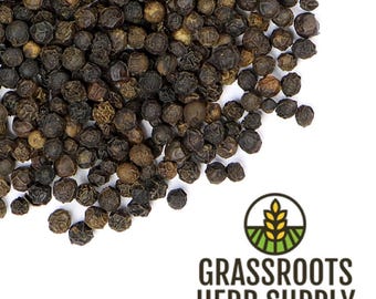 May include: A close-up view of black peppercorns, a common spice used in cooking. The peppercorns are scattered on a white background.
