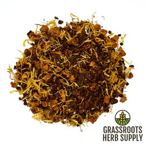 May include: A pile of dried herbs and botanicals, featuring a mix of dark brown, tan, and yellow elements. The blend includes what appears to be small pieces of bark, seeds, and flower petals. The Grassroots Herb Supply logo is visible in the lower right corner.