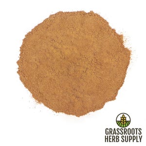 May include: A close-up view of a pile of ground cinnamon, a warm brown spice, on a white background. The cinnamon is finely ground and has a smooth texture.