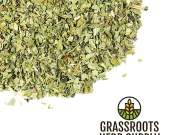 Puede incluir: Primer plano de un montón de hierbas verdes secas. Las hierbas están finamente picadas y tienen un color verde claro. Las hierbas están sobre un fondo blanco. El texto "GRASSROOTS HERB SUPPLY" es visible en la esquina inferior derecha de la imagen.