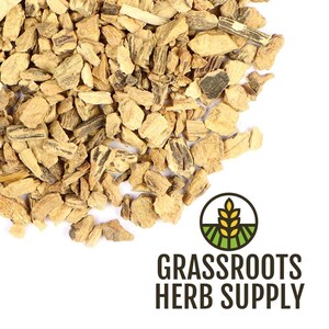 May include: Close-up of dried, chopped herbal pieces in shades of tan and brown. The pieces are irregularly shaped and textured. The image includes the text "GRASSROOTS HERB SUPPLY" with a logo of a wheat stalk over a green field.