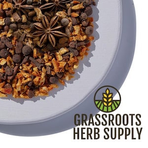 May include: A white ceramic plate filled with a blend of dried orange peel, star anise, cloves, and peppercorns. The plate is on a white background with the text "GRASSROOTS HERB SUPPLY" in brown text.