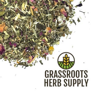 May include: A close-up of a blend of dried herbs and flowers, including green leaves, pink rose petals, and yellow chamomile flowers. The herbs are scattered on a white background with the text "GRASSROOTS HERB SUPPLY" in brown text below.
