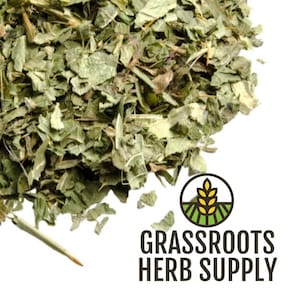 May include: Close-up of dried green herbs, possibly for culinary or medicinal use. The herbs are finely chopped and have a natural, earthy appearance. The image includes the logo for Grassroots Herb Supply.