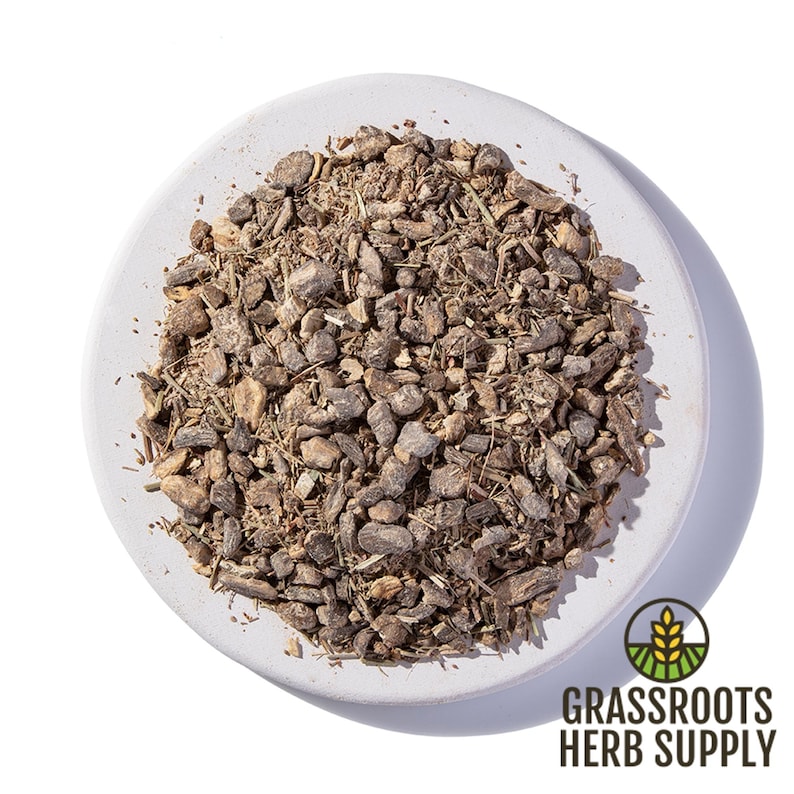 May include: A close-up view of a pile of dried, brown, and tan herbal roots and stems on a white plate. The plate is on a white background. The text "GRASSROOTS HERB SUPPLY" is visible in the lower right corner of the image.