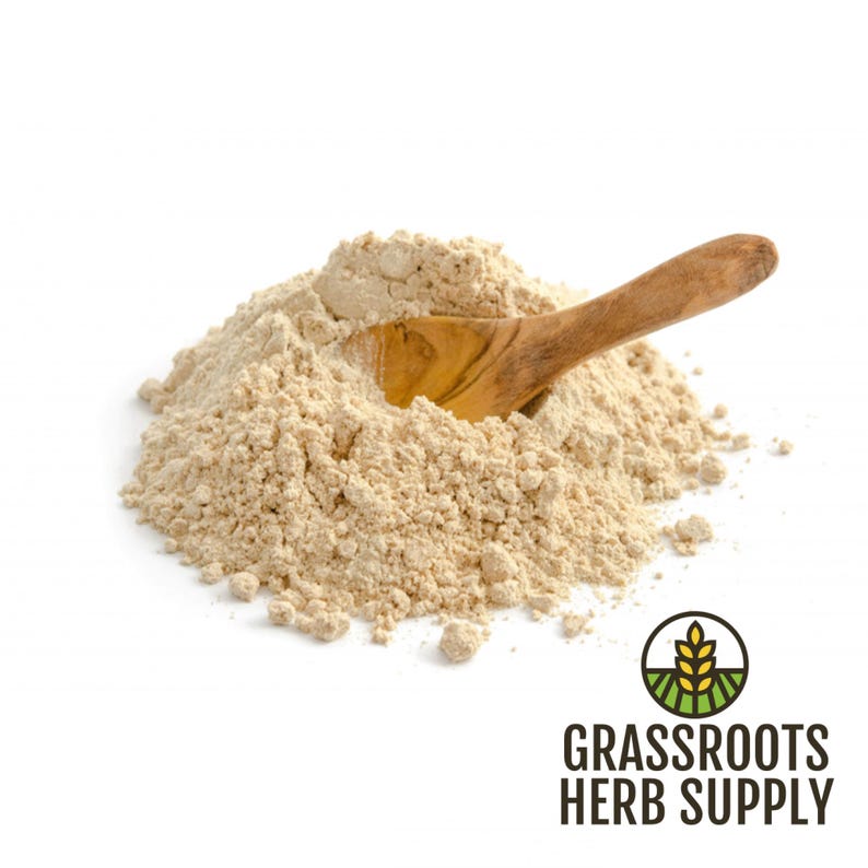 Pode incluir: Um monte de p&oacute; de maca marrom claro com uma colher de madeira em cima. O p&oacute; &eacute; um suplemento alimentar popular.