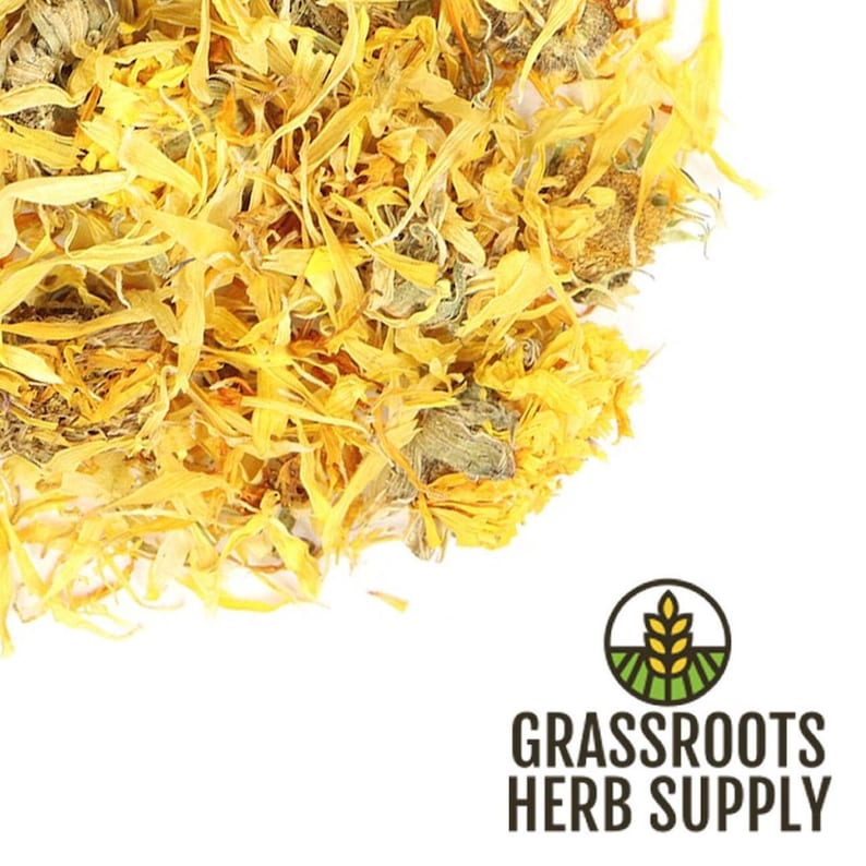 May include: Dried calendula petals, a bright yellow and orange color, in a pile on a white background. The petals are loose and have a slightly textured appearance. The image is labeled "GRASSROOTS HERB SUPPLY".