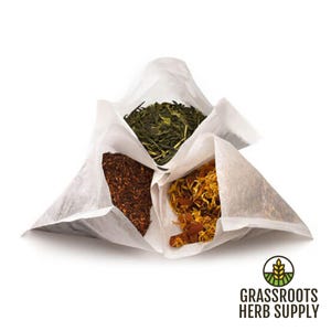 May include: Three open white tea bags, each filled with different dried herbs. One bag contains green tea leaves, another has reddish-brown rooibos, and the third holds yellow calendula flowers. The Grassroots Herb Supply logo is in the bottom right.