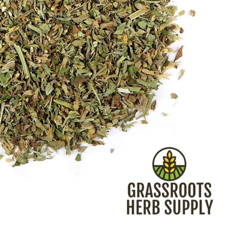 May include: A close-up of dried green herbs, likely a blend of various herbs, for culinary or medicinal use. The herbs are scattered on a white surface. The image includes the text "GRASSROOTS HERB SUPPLY".