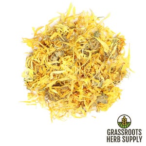 May include: A close-up of a pile of dried calendula petals. The petals are a bright yellow color and have a slightly green tint. The petals are arranged in a loose pile and are ready to be used for crafting or herbal remedies.