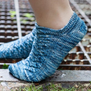 Puede incluir: Un par de calcetines de tobillo azules y blancos con un patrón de punto de cable. Los calcetines están hechos de un material suave y cómodo y son perfectos para el uso diario.