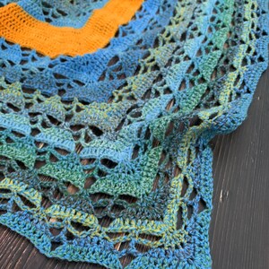 May include: A crocheted shawl with a gradient of blue, green, and yellow colors. The shawl is made with a delicate openwork stitch pattern.