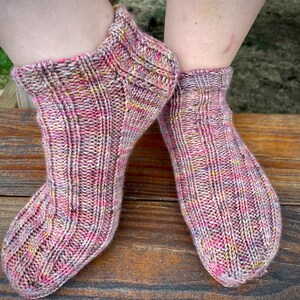 Könnte beinhalten: Ein Paar gestrickte Socken in Rosa und Gelb mit Rippenstruktur.