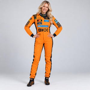 May include: A bright orange racing jumpsuit featuring black side panels and a high collar. The garment is covered in various sponsor logos including OKX, Dell Technologies, Cisco, and Android, with black racing shoes completing the ensemble.