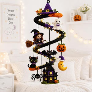 Könnte beinhalten: Ein spiralförmiges Halloween-Mobile mit gehäkelten Figuren, darunter eine Hexe mit Besen, ein Geist, eine schwarze Katze, eine Spinne, ein Kürbis, eine Mondsichel und ein Spukhaus, die alle unter einem violetten Hexenhut hängen.