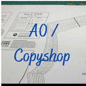 May include: A close-up of a sewing pattern with the text "Mile End" and "AO/CopyShop". The pattern is printed on white paper and features a series of lines and curves.