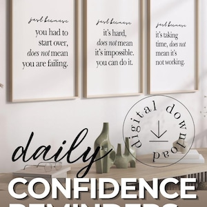May include: Three framed prints with motivational quotes in black script. The prints are displayed above a wooden surface with decorative items. The words "daily CONFIDENCE REMINDERS" are also visible.