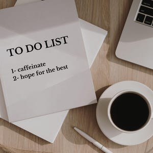 Pode incluir: Uma lista de tarefas brancas sobre uma mesa de madeira com uma x&iacute;cara de caf&eacute; e um laptop. A lista diz "TO DO LIST 1- caffeinate 2- hope for the best".